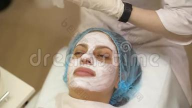 年轻女子接受美容药物治疗，特写。 美容师双手在工作，清洁皮肤，做面部按摩。